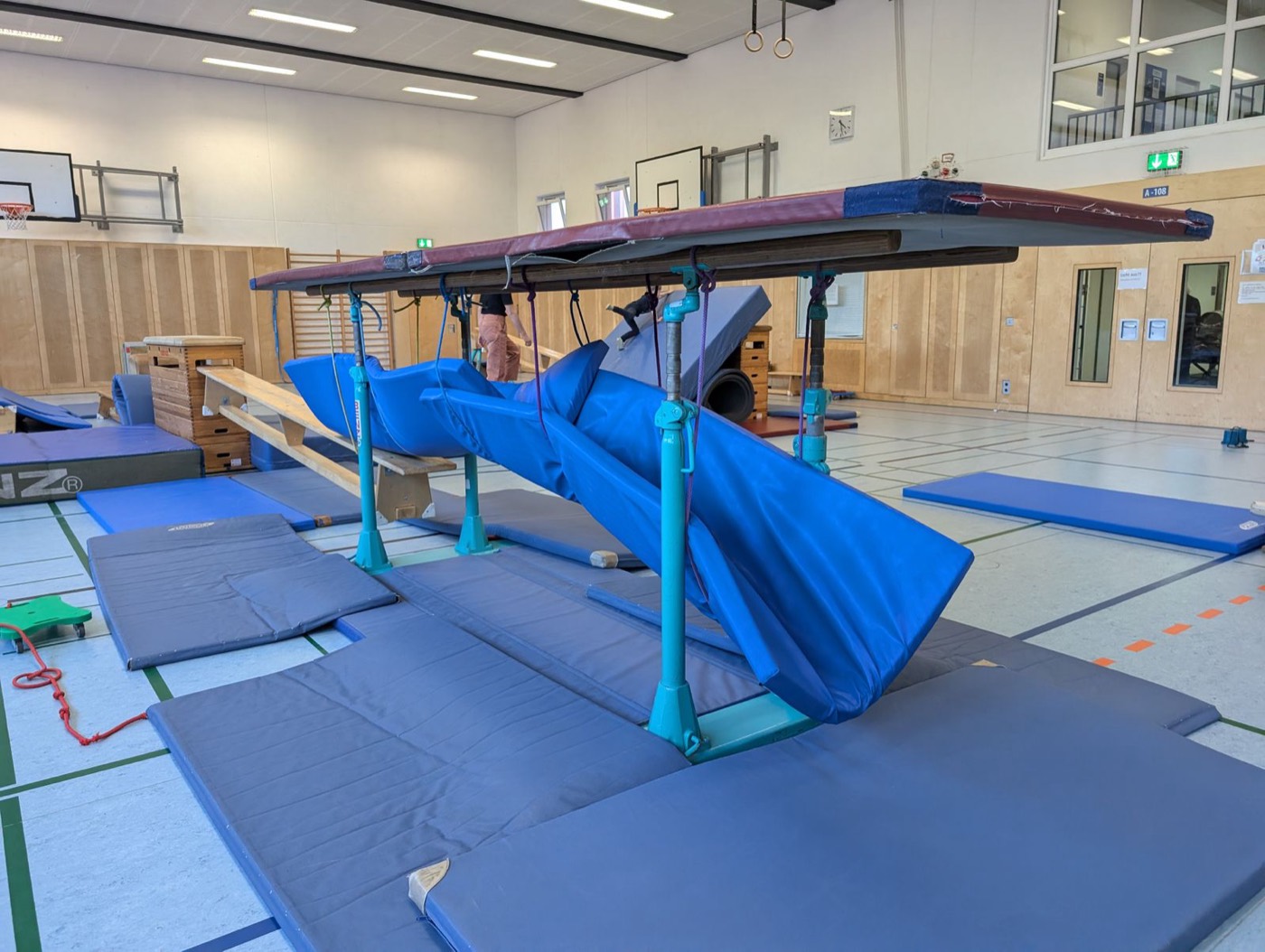 Blaue Rutschfläche und Balancierbalken bilden eine Bewegungslandschaft in der Turnhalle.