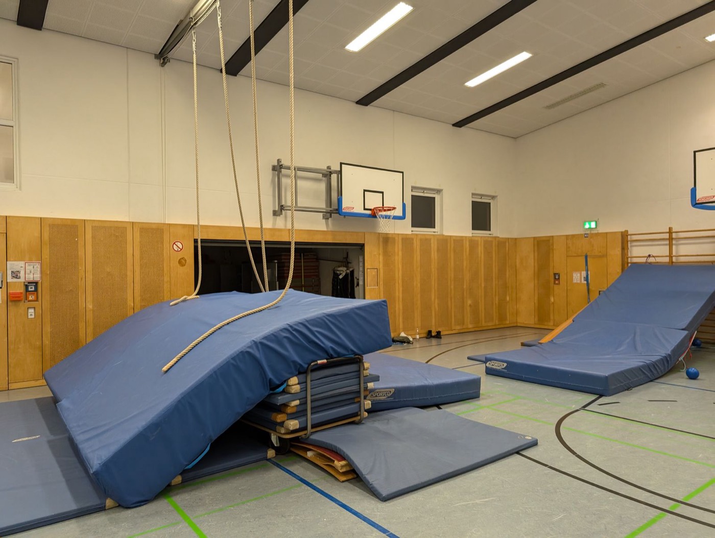 Ein großer Weichbodenberg mit Kletterseilen steht in der Hallenmitte.
